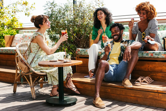 Diverse friends resting on terrace and talking