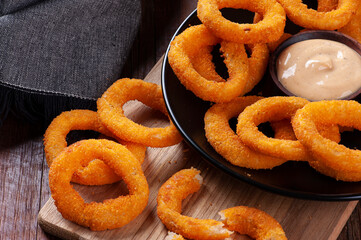 Delicious homemade crunchy fried onion rings with spicy sauce