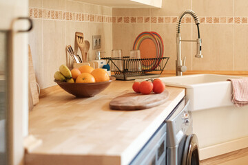Close up of modern kitchen with sink and faucet, fruits and vegetables on the counter.