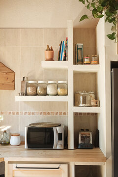 Modern kitchen with microwave oven, toaster and jars with legumes