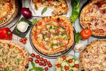 Set of pizzas and Italian dishes. Calzone, arrabiata pizza, carbonara pizza, rucola pizza, cherry tomato branch, burrata, garlic and peppers.