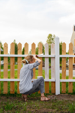Tired female painter wiping sweat near fence