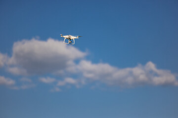 Fototapeta na wymiar Unmanned aerial vehicle against the blue sky and clouds - drone in the air