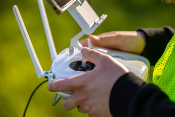 An unmanned aerial vehicle pilot in a reflective vest controls the drone using a flight controller