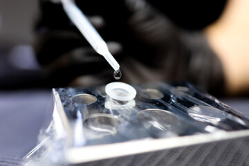 tattoo artist pipette adds a drop of water to stir the pigment