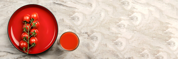A glass of tomato juice and a branch of small tomatoes banner. Cherry tomatoes in a red plate on a...
