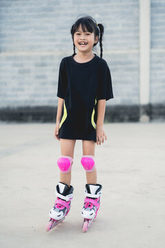 Asian girl playing rollerblades on a concrete patio