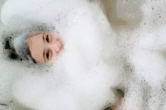 Girl's Face Peeking out from Bubbles in the Bath Tub