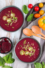Top view of cold beetroot gazpacho chilled soup with tomatoes cherry, mint leaves and bell peppers. It's a cold blended mix assortment of raw vegetables. It's a refreshing and cool soup eat in summer
