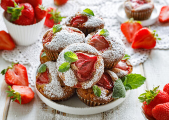 Strawberry muffins sprinkled with powdered sugar and decorated with fresh mint leaves. close-up. Delicious homemade dessert.
