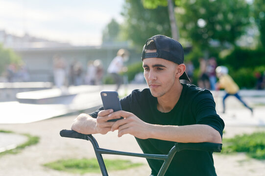 Smiling young man on a BMX checking his phone - Powered by Adobe