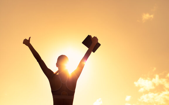 silhouette of inspire female holding up book to the sky with thumbs up. Education, and religious belief concept