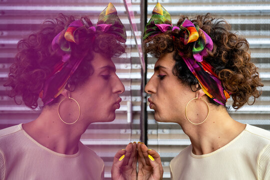 Portrait of a transgender woman blowing an air kiss and reflected on pink background - Powered by Adobe