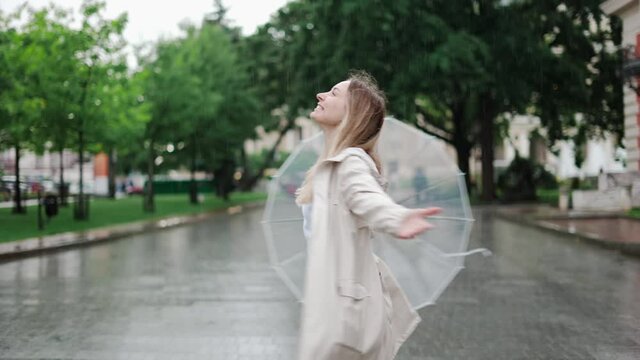 Carefree young blonde woman lets the refreshing spring rain fall down on her