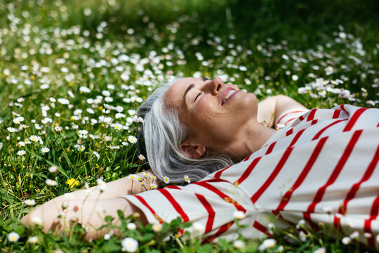 Delighted middle aged female lying on grass
