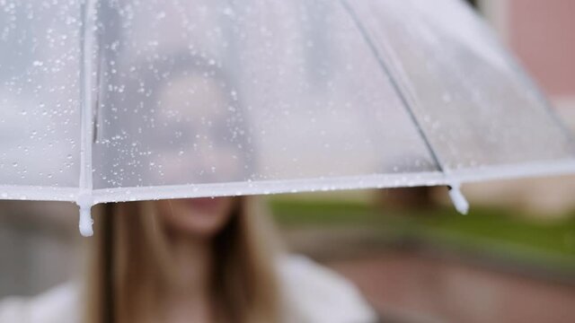 Portrait of a blurred woman standing under trasparent umbrella