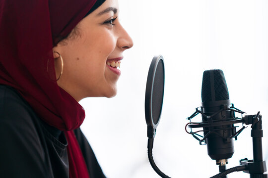 Smiling Arab woman recoding podcast and talking in mic