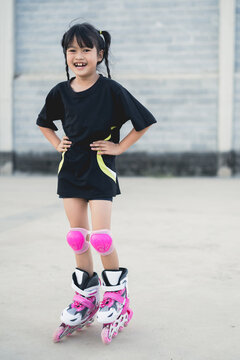 Asian girl playing rollerblades on a concrete patio