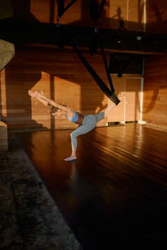 woman practicing aeral yoga on studio at sunset