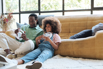 Dad and her daughter playing video games with a steering wheel at home
