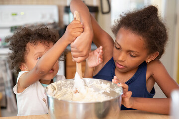 Young girl and her sister stirring cupcake batter