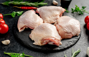 raw chicken thighs with spices and herbs on a stone background