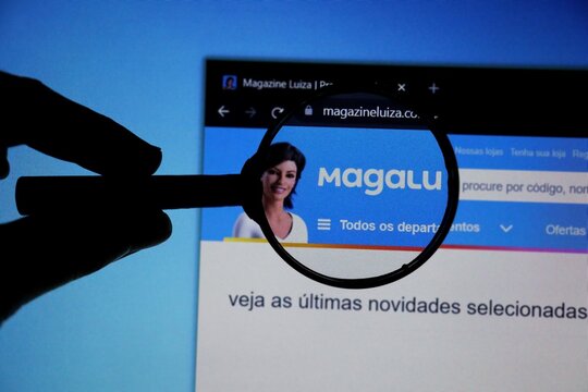 Bahia, Brazil - July 8, 2021: Homepage of Magalu Website magnified on logo with magnifying glass. Brazilian company. Magazine Luiza logo.