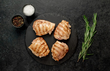 grilled skinless chicken thighs with spices and herbs on a stone background