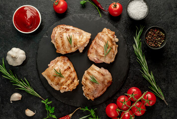 Fototapeta na wymiar grilled skinless chicken thighs with spices and herbs on a stone background