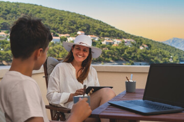 Working on a vacation.A woman holding a tablet in the hands and chatting with a family member on a...