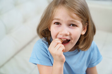 Little girl shows a reeling tooth. changing milk teeth to indigenous teeth.