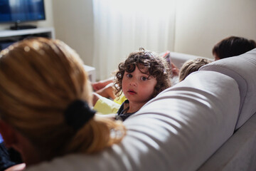 Young mother reading a book while her kids using a digital tablet