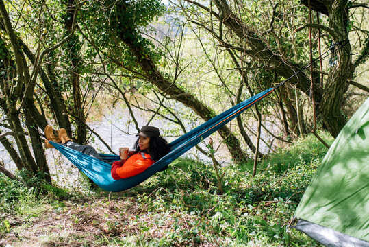 black woman in hammock at campsite with tent