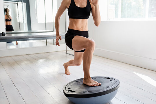 Crop sportswoman practicing on bosu ball in gym