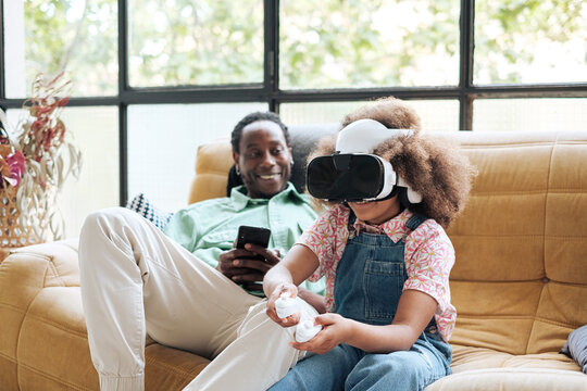 Child using virtual reality headset close to her father 