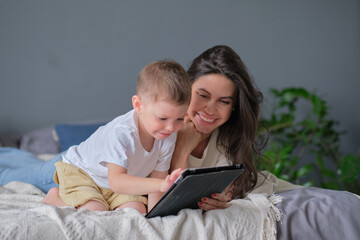 mother and son with tablet at home. Mother showing media content on line to her son in a tablet in the living room in a house interior