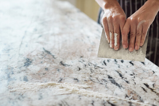 Crop baker scraping marble table