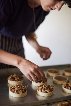 Crop woman decorating tarts with walnuts