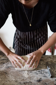 Crop woman kneading dough during work in bakery