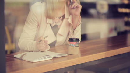 Cafe city lifestyle woman on phone drinking coffee talking on smartphone app sitting indoor in trendy urban cafe. in vintage color tone