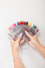 Vertical cropped shot of female hands with manicure color palette of nail polish