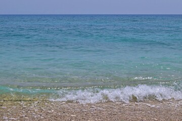 Calm waves of crystal sea water on pebble beach