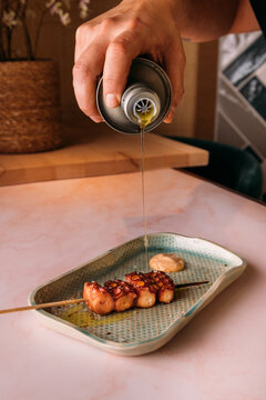 Cook pouring olive oil over a delicious octopus skewer