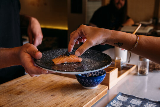 Cook offering a salmon nigiri to an anonymous person