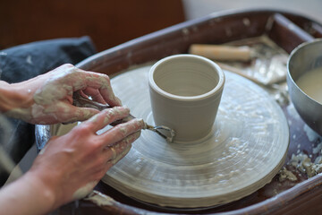 Fototapeta na wymiar Female Potter creating a earthen jar on a Potter's wheel