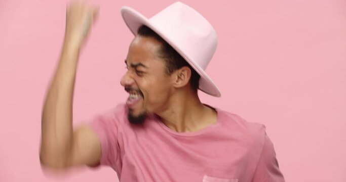 Young happy black man looking camera and making winner gesture isolated over pink 