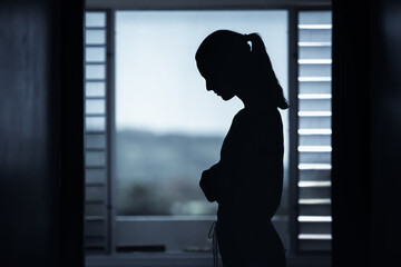 silhouette of sad young woman at home. Depression, mental health, and sadness concept. 