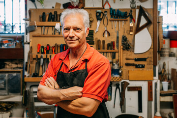 Senior guitar maker looking at camera