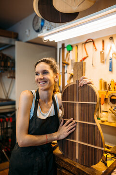 Young Woman Luthier holding a guitar template