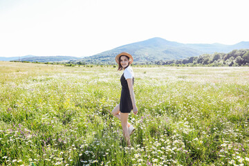 Beautiful woman in dress walks travels on the field of daisies